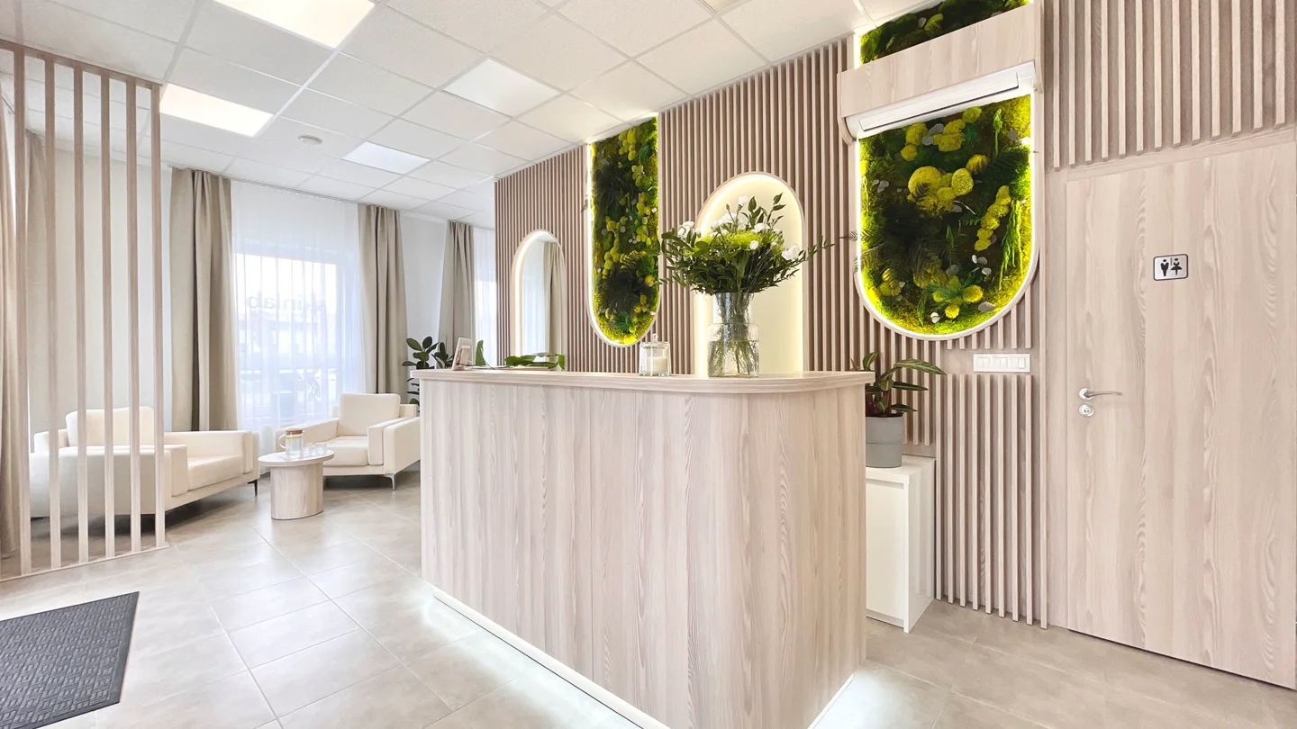 Skutočná recepcia Skinlab: oblý drevený pult, machová stena a presvetlený interiér